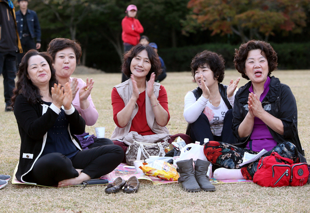 ▲ 마음만은 청춘인 중년 여성들이 잔디광장에 앉아 인기가수의 공연을 즐기고 있다.