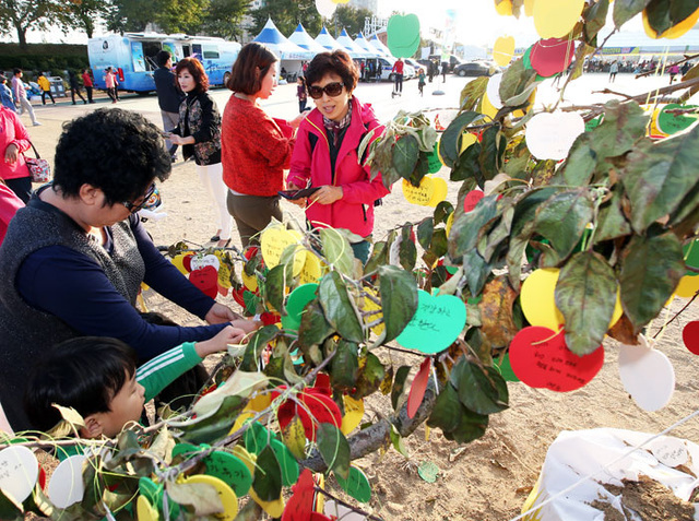 ▲ 세계 활축제 행사장에 마련된 소원나무에 관광객들이 작은 소원을 적어 걸고 있다.