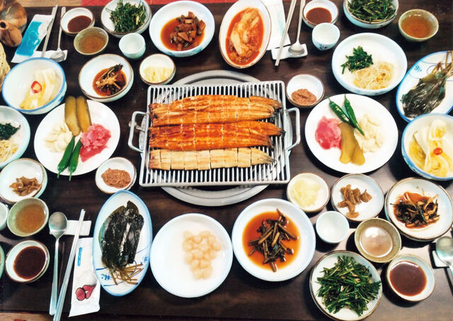 ▲ 숯불에 구워지고 있는 민물장어(위에서부터 간장구이·고추장구이·소금구이)와 갖은 채소 반찬들.