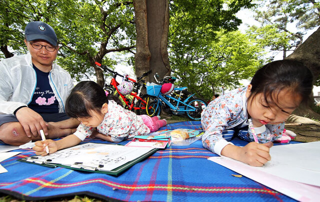 ▲ 7일 경주 황성공원에서 열린 경북어린이 백일장 및 사생대회에 참가한 자매의 그림 그리는 모습을 아버지가 흐뭇한 표정으로 바라보고 있다.