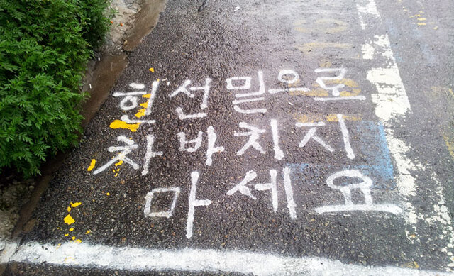 ▲ 바닥에 쓰인 글자의 `힌 선`은 `흰 선`으로, `바치지`는 `받치지`로 쓰는 것이 옳다. 어문규정 혹은 맞춤법은 의사소통을 원활하게 할 수 있도록 돕는다. 그러나 맞춤법이 의사소통을 원활하게 만들 수 있을지는 모르지만, 저 말끔한 말로 진심까지 전달하기는 어렵다. 왜냐하면 법규, 규정이라고 불리는 것들은 인간의 실제적 삶보다 언제나 더 늦게 도착하기 때문이다.