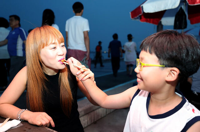 ▲ 축제 현장에서 아들이 엄마에게 검은돌장어 구이를 먹여주고 있다.