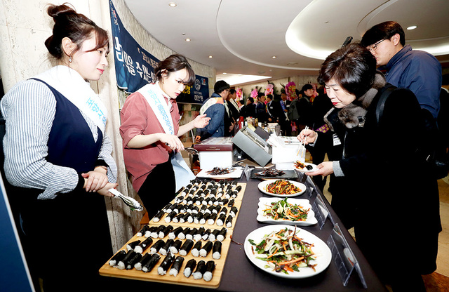 행사장 입구에 마련된 지역특산품 전시장에서 출향인이 과메기 요리를 맛보고 있다.