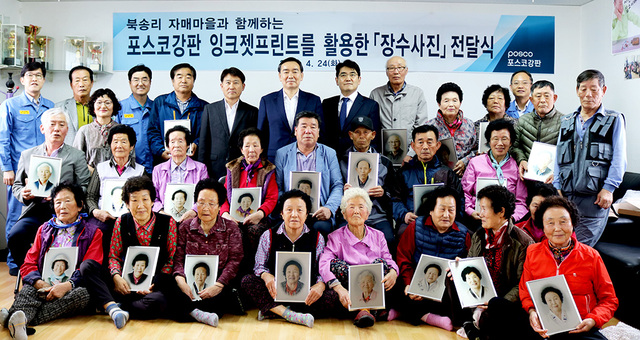 포스코강판이 포스아트를 활용해 제작한 장수사진을 받은 포항시 북구 흥해읍 북송리 마을 주민들이 사진을 들고 기념촬영을 하고 있다.  /포스코강판 제공