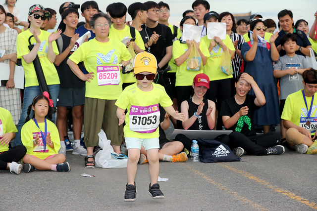 꼬마 아가씨가 5km 완주 후 인기 가수 공연이 펼쳐진 애프터 파티를 신나게 즐기고 있다.