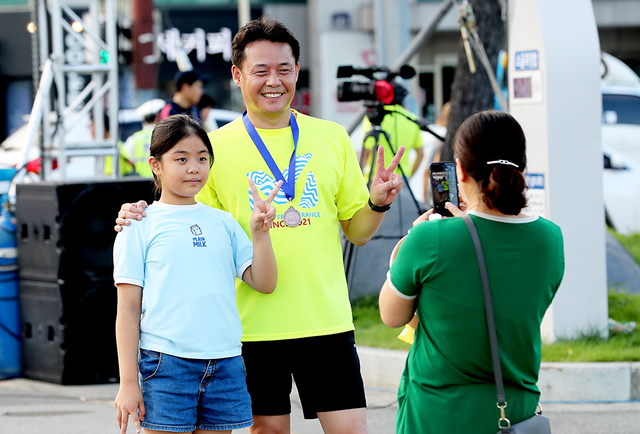 완주 기념 메달을 목에 건 한 참가자가 딸과 함께 인증사진을 찍고 있다.