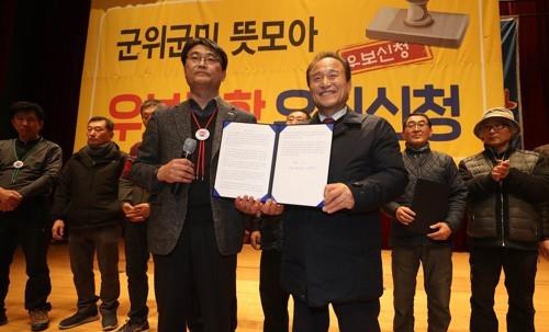 대구경북 통합신공항 최종이전지 선정 주민 투표가 열린 지난 21일 오후 경북 군위군 삼국유사교육문화회관에서 김영만 군위군수(앞줄 오른쪽)가 신공항 후보지를 우보면으로 신청해 달라는 군민 성명서를 전달받고 있다.