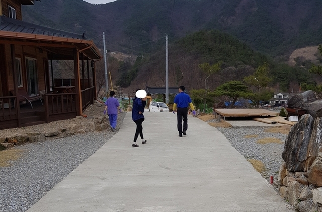 코로나19 경증환자로 추정되는 사람(가운데)을 생활치료센터 관계자가 황급히 데려가고 있다.