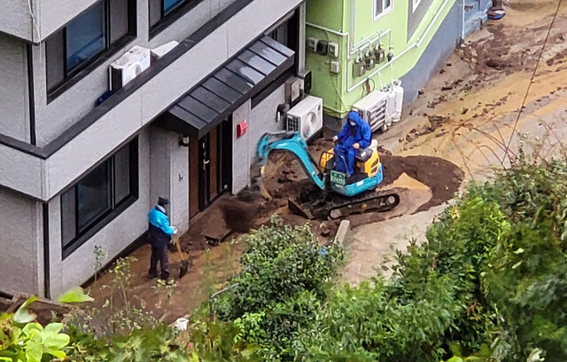 토사와 흙탕물이 유입된 A씨 주택 굴삭기로 토사를 치우고 있다 /김두한 기자
