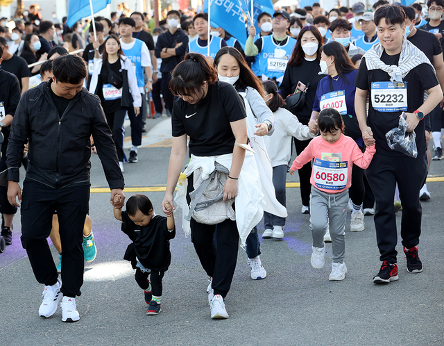 어린 자녀의 손을 잡은 젊은 부부들이 5km 완주에 도전하고 있다.