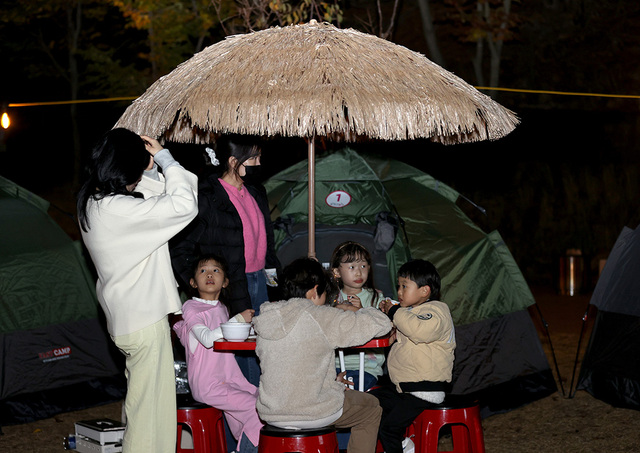 　텐트 앞에 설치된 파라솔 테이블에서 아이들이 옹기종기 모여 간식을 먹고 있다.
