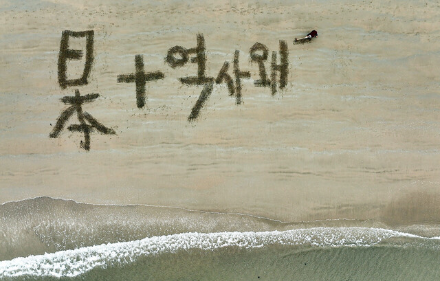 모래사장에 글을 쓰는 쌍산 김동욱 서예가. 갈고리를 이용해 모래사장을 긁어서 글을 쓰고 있다.  글 규모를 짐작할 수 있다 /쌍산 김동욱서예가 제공 