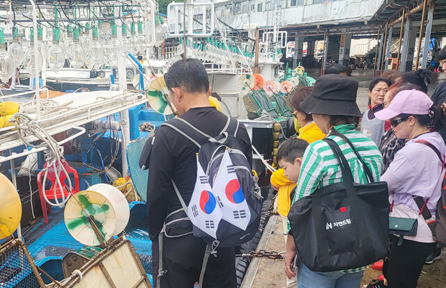 관광객들이 살아있는 오징어를 보고 신기해 하고 있다.