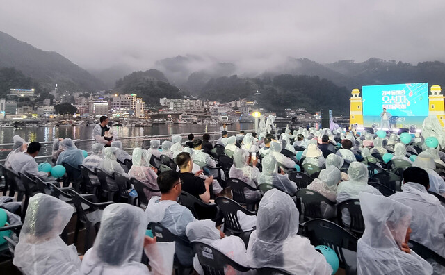 비가 오는 가운데 많은 주민과 관광객들이 어울려 오선지 등대음악회를 즐기고 있다.