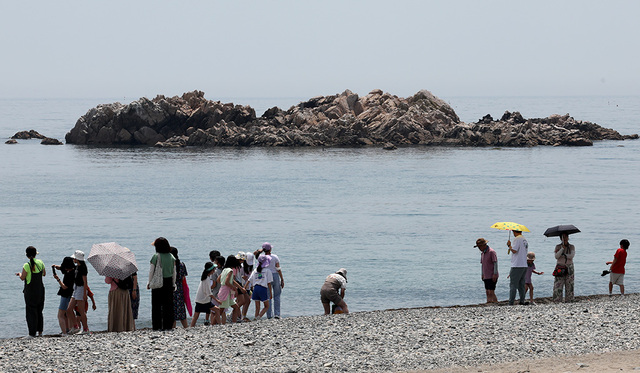 경주 봉길리 해변을 찾은 사람들이 문무왕릉을 바라보고 있다. /사진 이용선기자