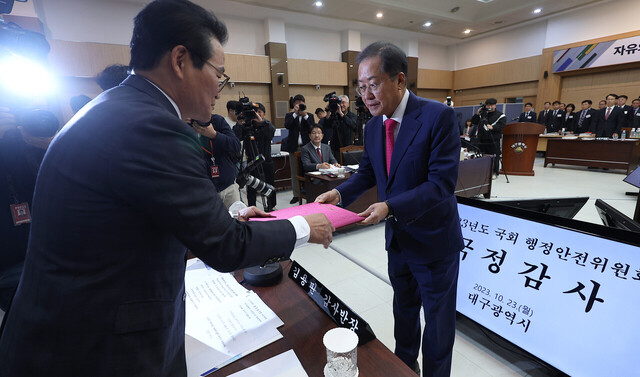 홍준표 대구시장(오른쪽)이 23일 대구시청 산격청사에서 열린 국회 행정안전위원회의 대구시에 대한 국정감사에서 국민의힘 김용판 의원에게 선서문을 제출하고 있다. /연합뉴스