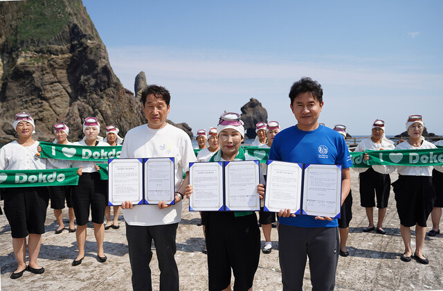 독도현지에서 경북문화관광공사 김남일 사장(왼쪽)과 경북해녀협회 성정희 회장,  경북대 블루카본 융합연구센터 윤호성(오른쪽) 센터장이  ‘해양생태관광 활성화와 해양관광 전문인력 양성’을 위한 업무협약을 체결하고 있다. /경북문화관광공사