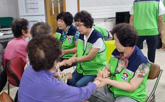 어르신들에게 손 마사지를 해주는 자원봉사자들./울릉군자원봉사센터