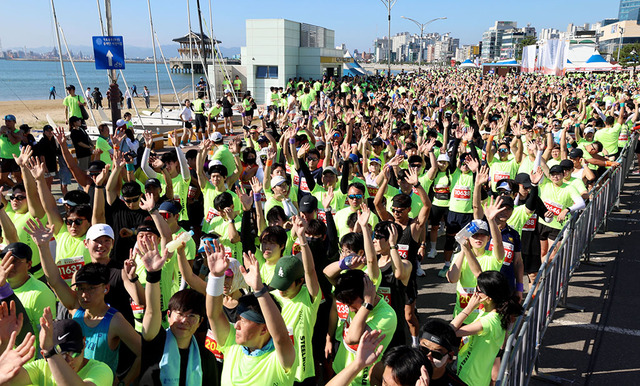 수천 명의 10km 참가자들이 출발에 앞서 손을 들어 환호하고 있다.
