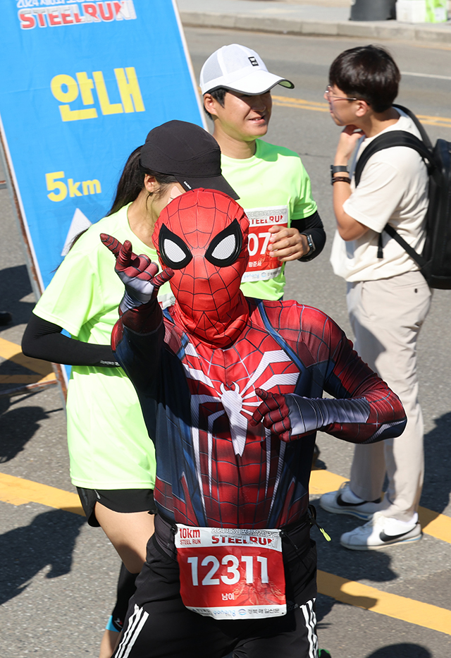 스파이더맨 복장의 10km 참가자가 카메라를 향해 포즈를 취하고 있다.