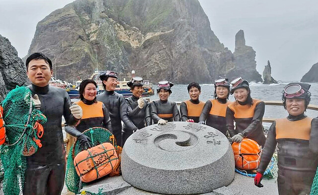 제주해녀들이 독도 물질 시연 후 대한민국 영토 동쪽 땅끝 표지석에서 기념촬영을 하고 있다.