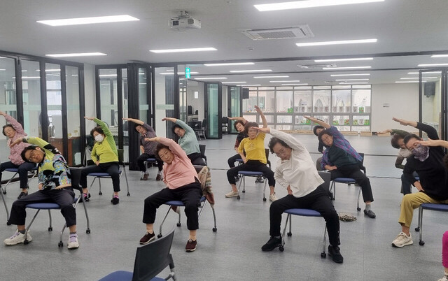 울릉도 어르신들이 의자에 앉아 건강체조를 하고 있다./울릉군