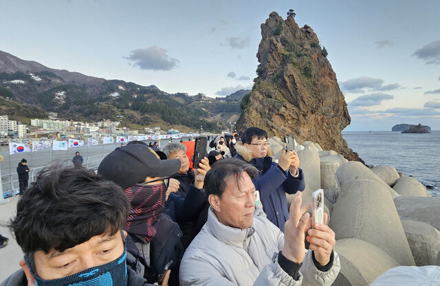 저동항 촛대암에 모인 해맞이 관광객들이 휴대폰으로 일출 모습을 촬영하고 있다. /김두한 기자 