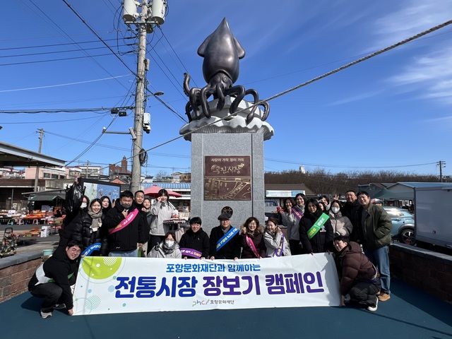 포항문화재단 임직원들의 청하 공진시장 입구 오징어 동상 앞에서의 기념촬영 모습. /포항문화재단 제공