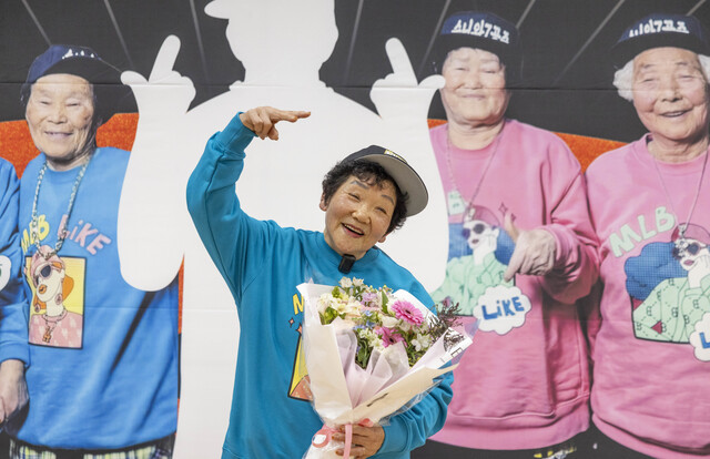 최종 합격자로 호명된 이선화 할머니가 꽃다발을 들고 환하게 웃으며 포즈를 취하고 있다. 무대 위에서 손가락으로 힙합 포즈를 취하며 ‘수니와칠공주’의 새로운 막내로서의 포부를 밝히고 있다. /칠곡군제공
